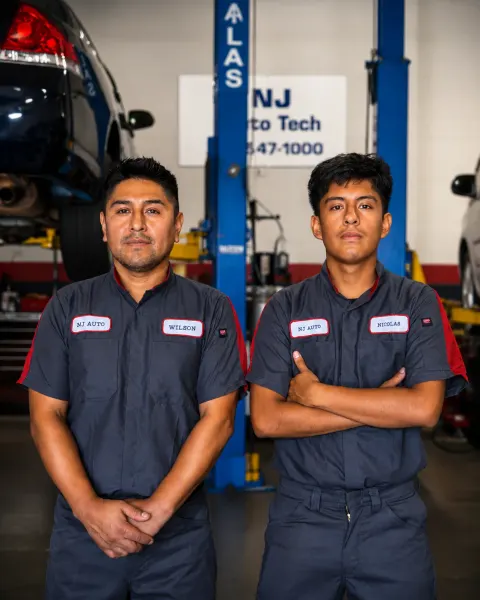 Technicians Wilson and Nicolas Sacasari standing together in the NJ Auto Tech Automotive Specialist service bay in Wappingers Falls, NY