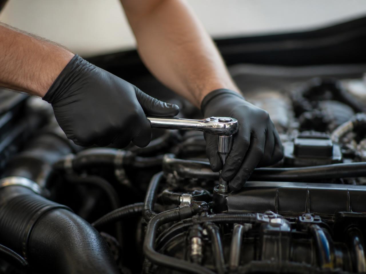 Mechanic using a ratchet wrench on an engine fastener during general auto repair